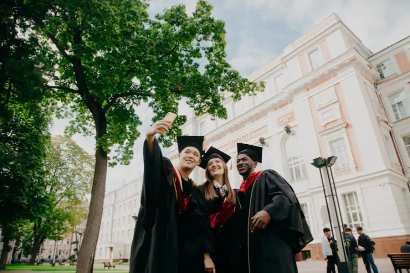 Graduates in caps and gowns celebrating outside a college building