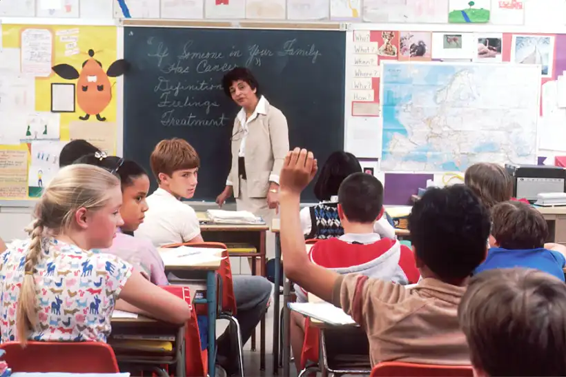 Children raising their hands in a bright school classroom